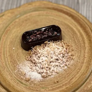 firm smooth cacao nibs topped rich dark chocolate haupia  with  textural crunch of almond cookie, coconut sugar and roasted coconut