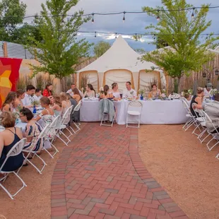 a group of people sitting at tables outside