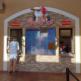 a man standing in front of a pizzeria