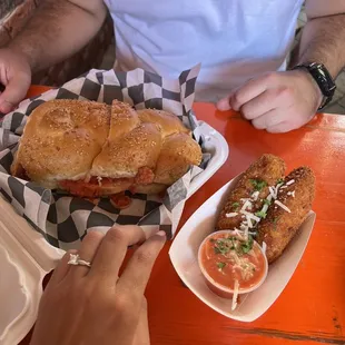 a person eating a sub sandwich and dipping sauce