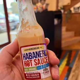 a hand holding a bottle of habaneen hot sauce