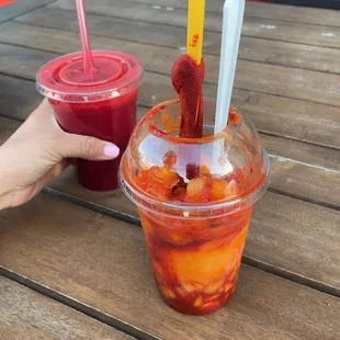 a person holding a plastic cup of fruit juice