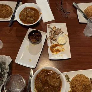 Stewed beef- upper right, center- empty appetizer platters (spicy plantain and lemon pepper wings), bottom- goat stew
