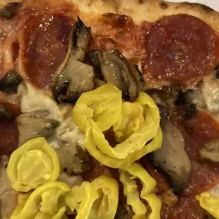 a slice of pizza with pepperoni, mushrooms, and jalapenos