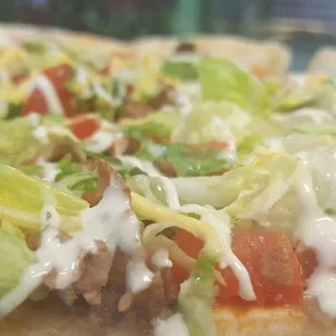a tasty looking pizza with lettuce, tomatoes, cheese, and other toppings