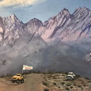 two jeeps on a dirt road with mountains in the background