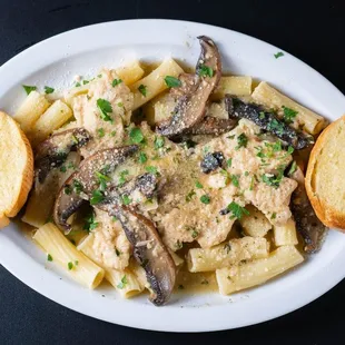 a plate of pasta with mushrooms and bread