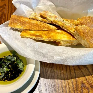 a basket of bread and a bowl of dipping sauce