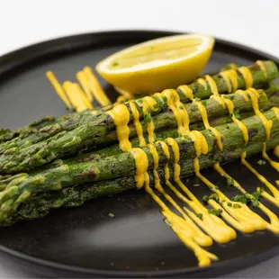 a plate of asparagus with mustard drizzle