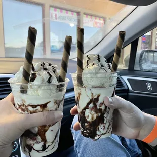 two people holding up two cups of ice cream