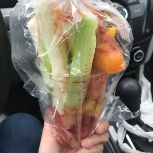 a person holding a cup of fruit