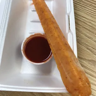 a hot dog on a stick in a styrofoam container