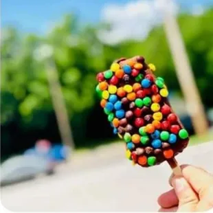 a hand holding a chocolate covered candy bar