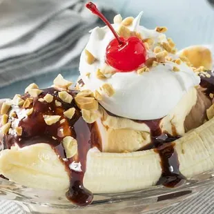 a banana split topped with whipped cream, chocolate sauce,