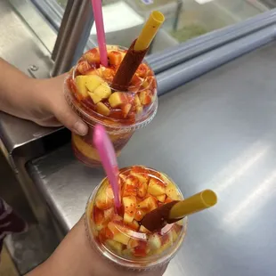 two people holding drinks in plastic cups