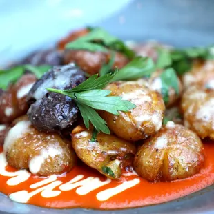 a plate of roasted potatoes with sauce and parsley