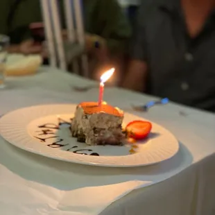 a slice of cake on a plate with a lit candle