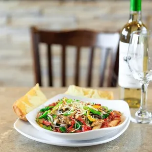 a plate of pasta and a bottle of wine