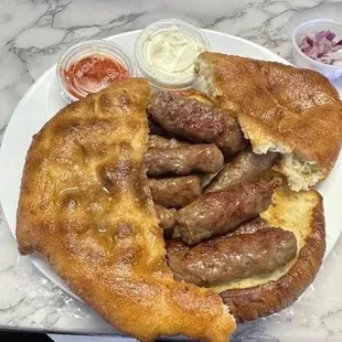 cevapi is our sausage Euro style meat with pita bread with a side of sour cream and our tomato paste sauce called ajvar and a side of onions