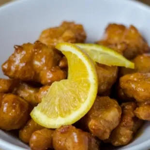 a bowl of chicken with a lemon wedge