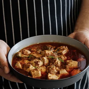 a person holding a bowl of stew