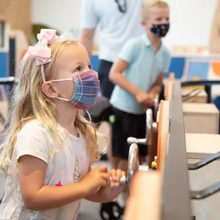 A young visitor spins one of the wheels on a large ball machine. Learn about science and cooperating with others at this fun exhibit!