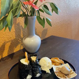 a plate of sushi and a vase of flowers