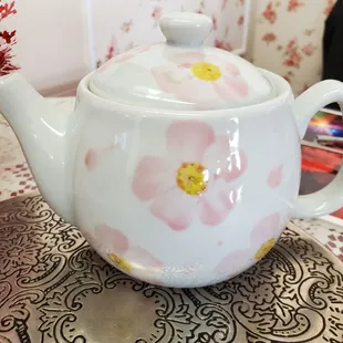 a white teapot with pink flowers