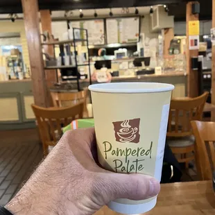 a hand holding a paper cup