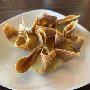 a plate of wontons on a wooden table