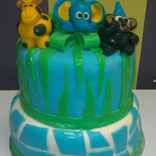 a blue and green cake with animals on top