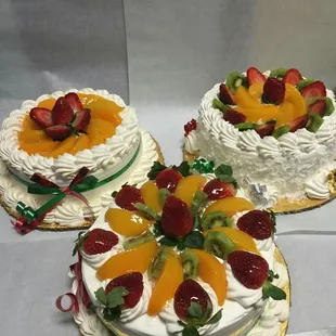 three cakes decorated with fresh fruit