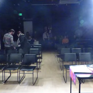 two people standing at a table in front of a screen