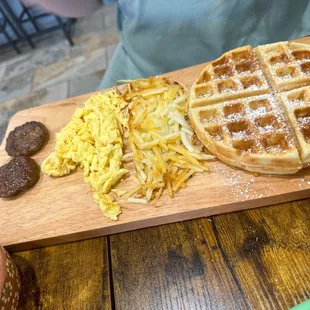 a waffle and eggs on a cutting board