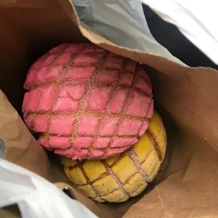 a pink and yellow pastry in a brown paper bag
