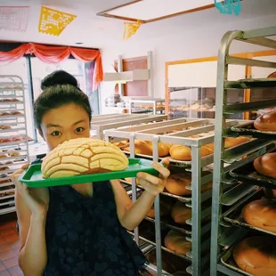 a woman holding a tray of donuts