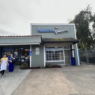 two people standing outside of a restaurant