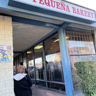 a woman standing in front of a bakery
