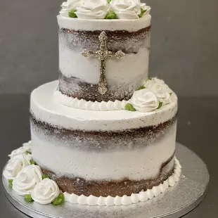 a three layer cake with white frosting and a cross on top