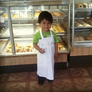 a little boy standing in front of a bakery
