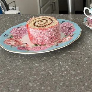 a piece of cake on a plate next to a cup of tea