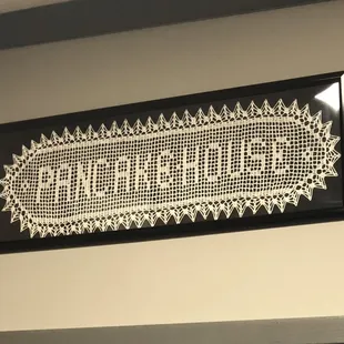a crocheted sign hanging on a wall