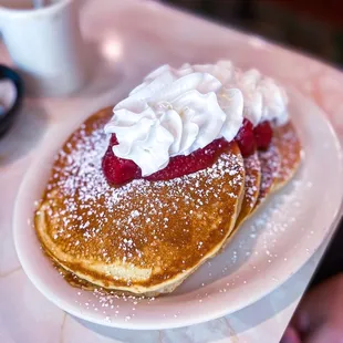 a pancake topped with whipped cream and raspberries