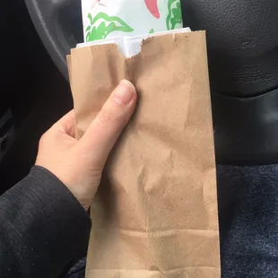 Burrito packed with napkins, large red hot sauce, and large green sauce.