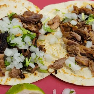 two pork tacos on a red plate