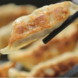 a close up of a dumpling being held with chopsticks