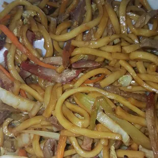 a white styrofoam container filled with noodles and meat