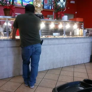 a man standing at the counter of a restaurant