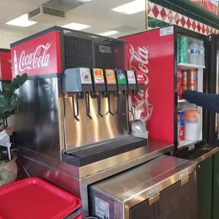 a man standing in front of a coca cola machine