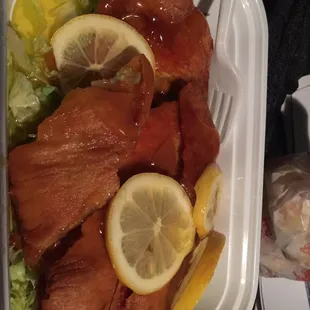a container of salmon with lemons and lettuce